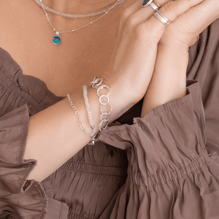 Close-up of a person's arm wearing the Artisan Hilltribes Fine Silver Link Bracelet | Everyday Radiance. The bracelet is shown worn with a Moonstone bracelet (sold separately)