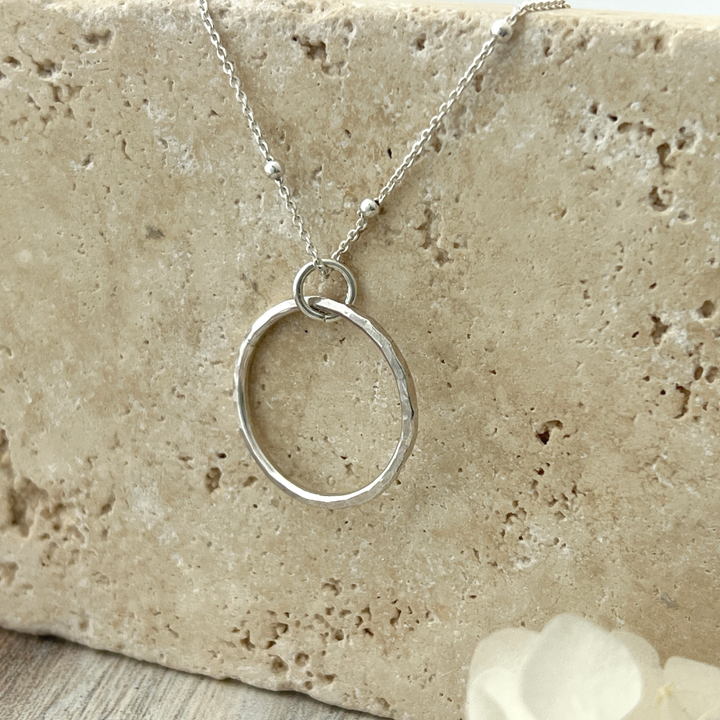 Circle Necklace. Made of sterling silver, this open-circle pendant features a stunning hand-hammered texture that reflects light. 