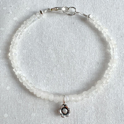 Rainbow Moonstone & Flower Charm Bracelet! Crafted with iridescent rainbow moonstone and a detailed silver flower charm, this beautiful bracelet shimmers in the sunlight and adds a touch of magic to your look.