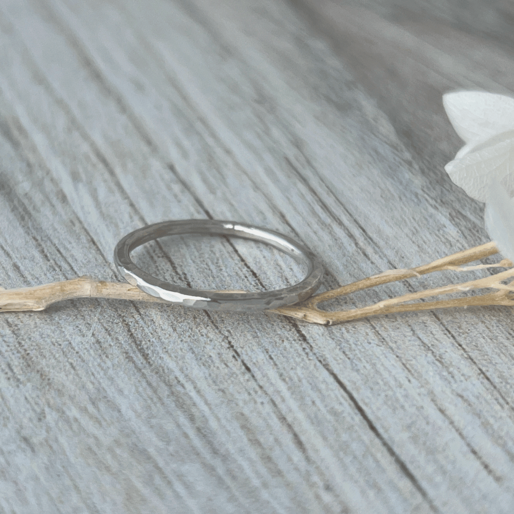 Thin Sterling Silver stacking ring on a wooden surface with a white flower