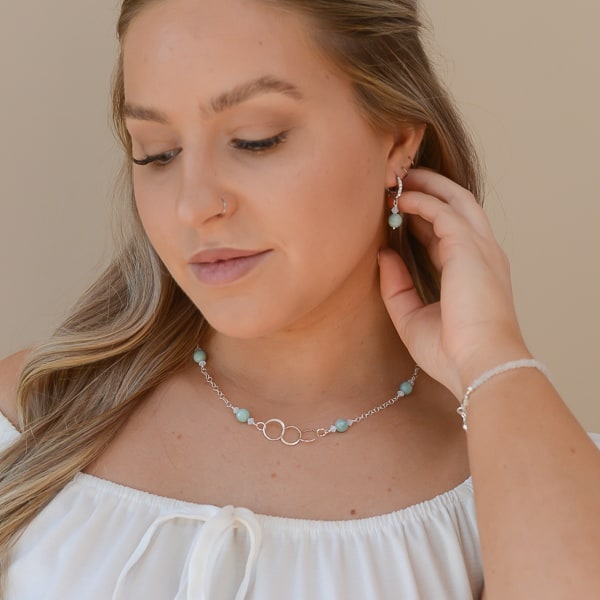 "Trinity" symbolizes the three interconnected circles, representing unity, balance, and completeness. "Reflection" aims to evoke feelings of elegance, sophistication, and self-reflection, highlighting its ethereal beauty. Shown with Matching Earrings and Rainbow Moonstone bracelet.