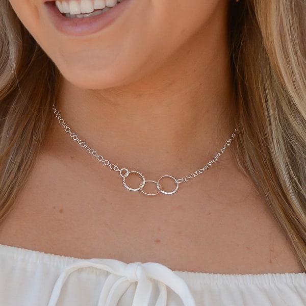 The subtle hammered texture brings alive a modern look that will make this necklace a jewelry box staple.  "Trinity" symbolizes the three interconnected circles, representing unity, balance, and completeness, which gives a unique and symbolic meaning to the necklace. "Reflection" aims to evoke feelings of elegance, sophistication, and self-reflection, highlighting the ethereal beauty of the necklace.