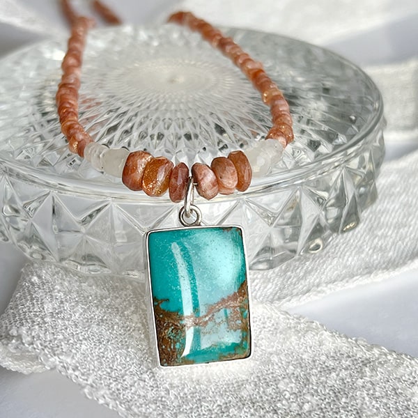 Experience radiance, joy, and tranquil energy with the Turquoise & Sunstone Beaded Pendant Necklace. The lustrous Sunstone in the necklace beautifully complements the copper-orange matrix of the Turquoise, resulting in a captivating statement piece that effortlessly enhances any ensemble.