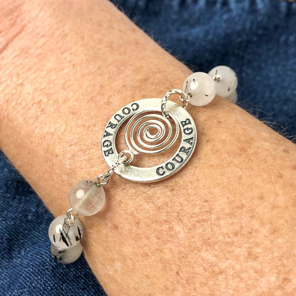 This highly polished sterling silver COURAGE affirmation circle charm is engraved on both sides and the lovely spiral drop. Milky white quartz with black inclusions of black tourmaline. On wrist.