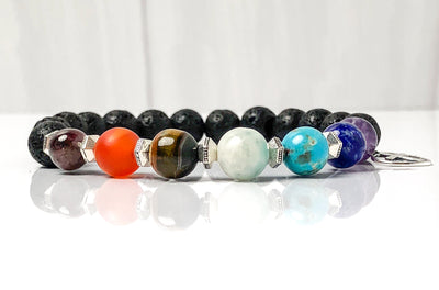 Semi-precious Gemstone 7 Chakra Bracelet, Sterling Silver Open Heart with Cross Charm, Lava Stone Bracelet, 8mm Beads, Handcrafted in CA.  This soul-inspired Chakra bracelet is handcrafted with 8mm lava & gemstone beads, Sterling Silver open heart cross charm, and antique silver-plated pewter spacers. Side view with reflection.