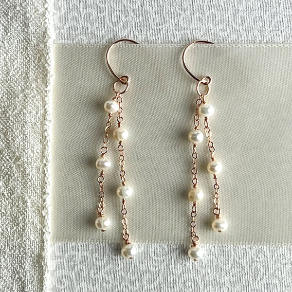 Add a hint of elegance to your bridal look with this timeless pair of dainty pearl earrings. Crafted from 14k rose gold-filled metals, these delicate drop earrings feature two strands of creamy freshwater pearls for a timelessly romantic design. Perfect for the modern bride or any special occasion, these earrings will add a finishing touch to your ensemble.