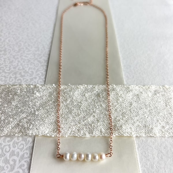 Capture the beauty of your special day with this delicate bridal necklace. Crafted with an adjustable 16-18" 14Kt rose-gold chain, adorned with freshwater pearls, this elegant piece is sure to add the perfect finishing touch to your look. This dainty pearl bar necklace is a lovely addition to your wedding day ensemble.