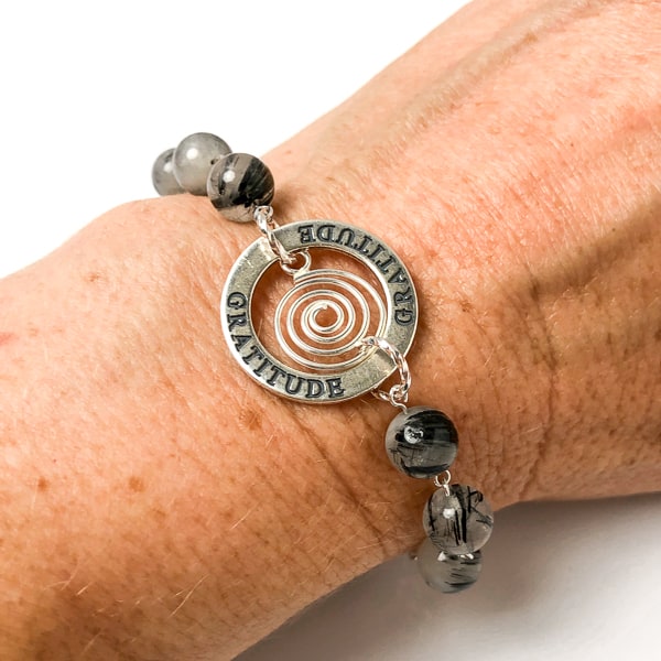 Is GRATITUDE your affirmation this year? This highly polished sterling silver circle charm is engraved on both sides and the lovely spiral drop gives it some whimsey. Milky white quartz with striking black needle-like inclusions of black tourmaline.  Handcrafted in CA. Shown on wrist.