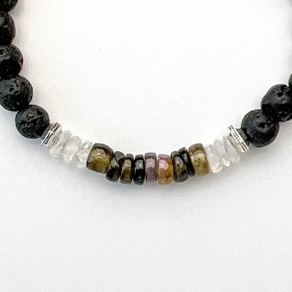 Heishi Shaped Tourmalines framed by Rainbow Moonstones highlight the translucent green and amber colors. Lava stone beads can absorb essential oil for relaxation. Front detail view.