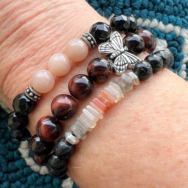 Butterfly Dreams Red Tigereye with Butterfly Charm bracelet. Deep rust red beads with whimsical butterfly charm. Worn on wrist stacked with other Novaura Jewelry gemstone bracelets.