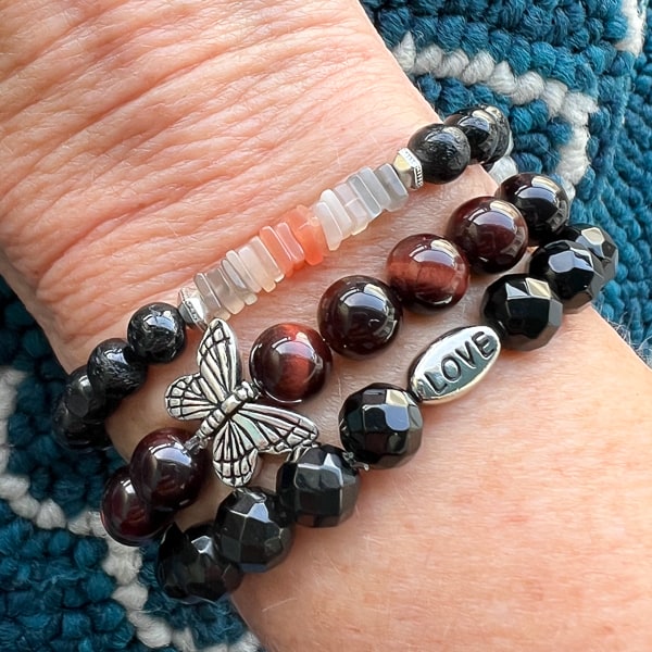 Love and Strength Onyx Bracelet worn with Novaura Jewelry Butterfly Dreams Red Tigereye and Lunar Shield stacking bracelets.