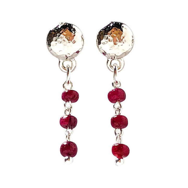 Delicate hammered finish for incredible texture to give a vintage flair to these earrings. Genuine Rubies-the queen of gems in a well-polished deep red and hand-cut rondelle shape. Lightweight in a classic round ear stud in rhodium-plated pewter. 