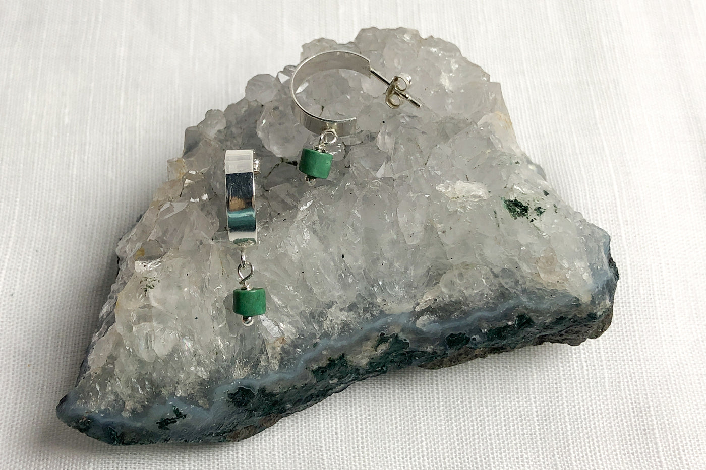 TURQUOISE-- get drawn by its beauty and its positivity - the small sea-green heishi beads create a color pop to these sterling silver half hoop ear studs. 
